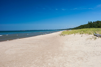 wide sandy beach on clear summer day with waves