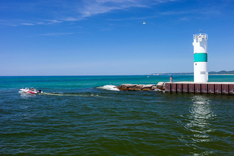 speed boat drives past the end of the pier and lighthouse
