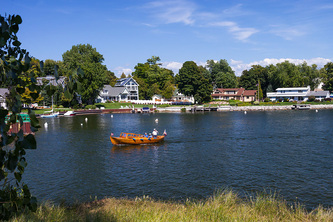 old style canoe in harbor with cottages on shore