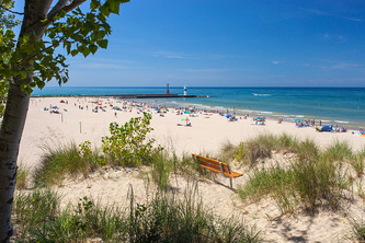 wide view of beach at state park with pier, beach-goers and Lake Michigan
